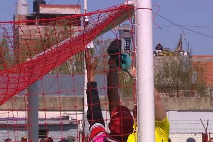 Entre el arquero de Colón y un auxiliar intentan reparar la red, en la cancha de Barracas Central