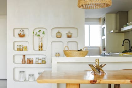 Entre el ornamento y lo funcional, los estantes son ideales para guardar la comida que Eugenia compra suelta. El juego de comedor estilo Wishbone es de Espacio Rumbita.