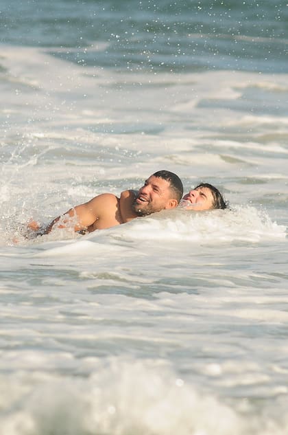 Entre las olas, padre e hijo a pura risa.