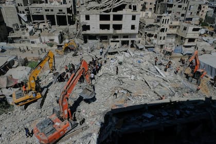 Equipos de Defensa Civil palestina buscan cuerpos y sobrevivientes entre los escombros de un edificio derrumbado, en Ciudad de Gaza