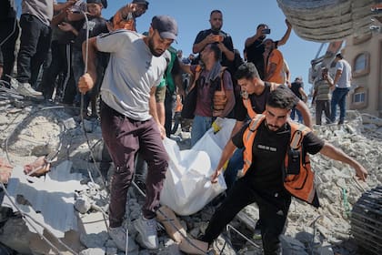 Equipos de Defensa Civil palestina retiran un cuerpo de entre los escombros de un edificio derrumbado, en Ciudad de Gaza