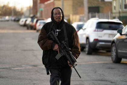 Erick Jordan camina por la calle con su fusil para ofrecer protección, el viernes 19 de noviembre de 2021, en Kenosha, Wisconsin. (AP Foto/Paul Sancya)
