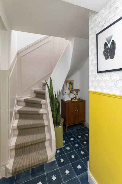 Escalera con alfombra de bouclé (Real Decoraciones) y, en el bajo, mueble antiguo con lámpara ‘Miffy’, icónico personaje infantil neerlandés