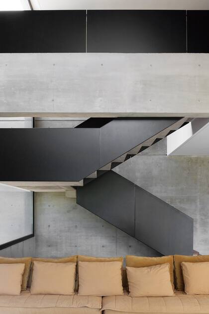 Escalera de hormigón con baranda de chapa pintada (Estudio Karina Kreth).