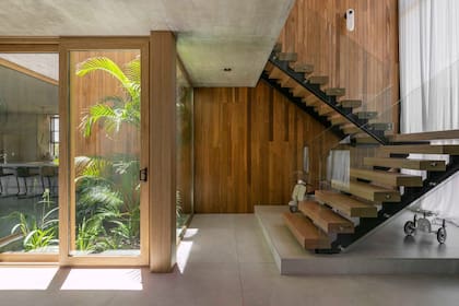Escalera (Minimal Hierro) con peldaños forrados en madera (Patagonia Flooring). Detrás, el revestimiento de lapacho (Alberto Pauletti + Grupo Forestal) disimula la presencia de la puerta hacia el playroom.