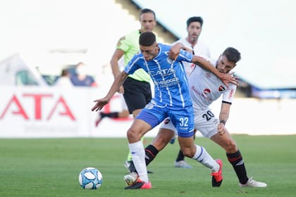 Gonzalo Abrego (Godoy Cruz) intenta llevarse la pelota ante la marca de Julián Fernández, volante central de Newells