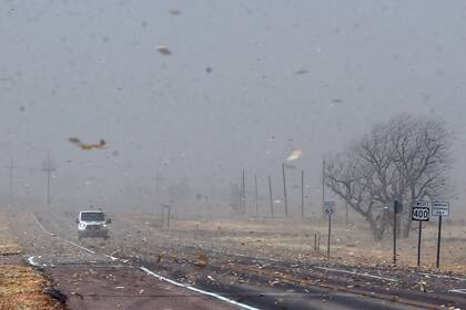 Escombros de las granjas cercanas vuelan sobre la autopista 400 el miércoles 15 de diciembre de 2021, entre Mullinville, Kansas, y Dodge City. (Travis Heying/The Wichita Eagle vía AP)