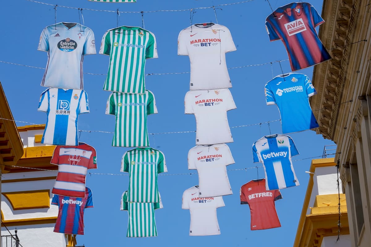 España, Sevilla: Modelos de las camisetas de los clubes de la Liga española de la Primera División cuelgan entre dos edificios en la calle Tetuán, para promover la reanudación de la liga, que se detuvo debido a la propagación de la pandemia de coronavirus, el jueves 11 de junio de 2020 en un partido
