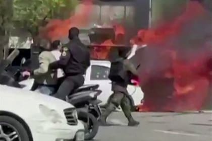 Esta captura de vídeo, tomada de imágenes generadas por usuarios y publicadas en redes sociales el 17 de marzo de 2026, muestra un vehículo de la unidad especial de la policía iraní en llamas en la plaza Enqelab de Teherán