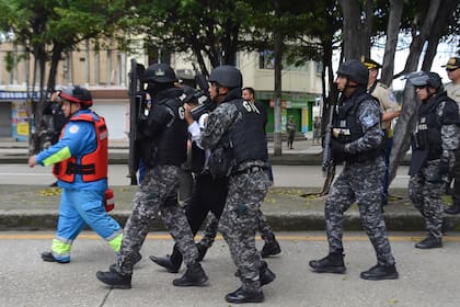 Esta foto de archivo difundida por la Policía Nacional de Ecuador muestra a agentes de policía llevando a un hombre con explosivos atados a su cuerpo en Guayaquil, Ecuador, el 30 de marzo de 2023.