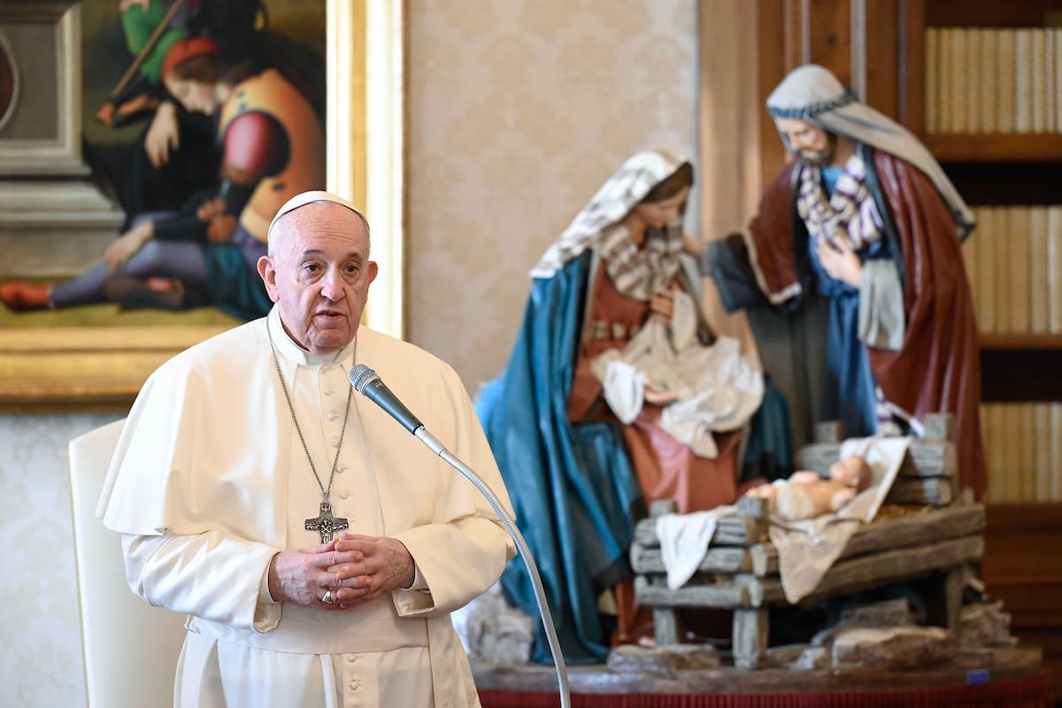 Esta foto tomada el 16 de diciembre de 2020 por Vatican Media muestra al Papa Francisco, de pie junto a un pesebre navideño, dirigiéndose a una audiencia privada semanal transmitida en vivo desde la biblioteca del palacio apostólico en El Vaticano