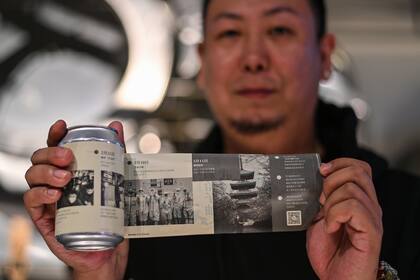 Esta foto tomada el 20 de noviembre de 2020 muestra a Wang Fan, fundador de la Cervecería No.18, posando con una de sus cervezas con imágenes de la lucha de la ciudad contra el coronavirus en Wuhan, provincia central de Hubei en China