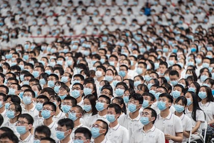 Esta foto tomada el 26 de septiembre de 2020 muestra a estudiantes de primer año con máscaras como medida preventiva contra el coronavirus durante una ceremonia de graduación en la Universidad de Wuhan