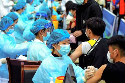Esta foto tomada el 30 de marzo de 2021 muestra al personal médico administrando una dosis de la vacuna contra el coronavirus de Sinovac en una universidad de Qingdao, en la provincia oriental de Shandong, en China