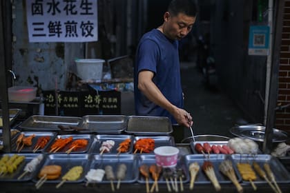 Esta foto tomada el 4 de agosto de 2020 muestra a un hombre sin mascarilla vendiendo comida en una calle de Wuhan en la provincia central china de Hubei
