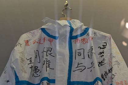 Esta foto tomada el 5 de agosto de 2020 muestra un traje firmado y donado por un equipo médico de Hainan que apoyó a la provincia de Hubei durante el cierre local de Covid-19, exhibido en una sala de la exposición del Museo de la Revolución de Wuhan