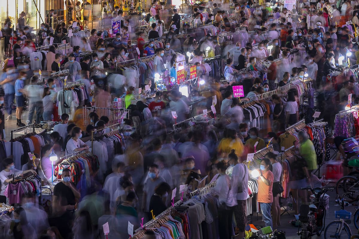 Esta foto tomada el 8 de junio de 2020 muestra a vendedores ambulantes que venden ropa en un mercado al aire libre ubicado en una calle en Wuhan, en la provincia central de Hubei en China