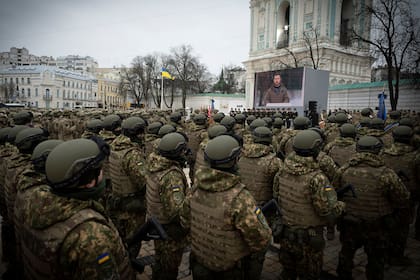 Esta foto tomada y difundida por el servicio de prensa presidencial ucraniano el 24 de febrero de 2023, muestra a militares ucranianos asistiendo a una ceremonia con el presidente ucraniano Volodimir Zelensky en una pantalla en la Plaza de Santa Sofía en Kiev, en el primer aniversario de la invasión rusa de Ucrania.