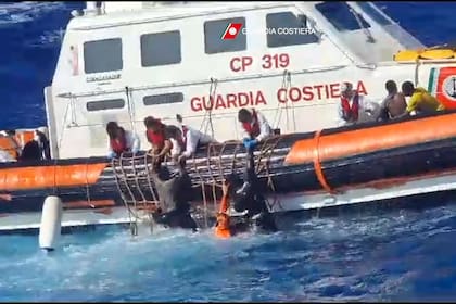 Esta fotografía de la Guardia Costera italiana muestra a los rescatadores ayudando a los migrantes a subir a un bote de rescate durante las operaciones que tuvieron lugar al sur de Lampedusa