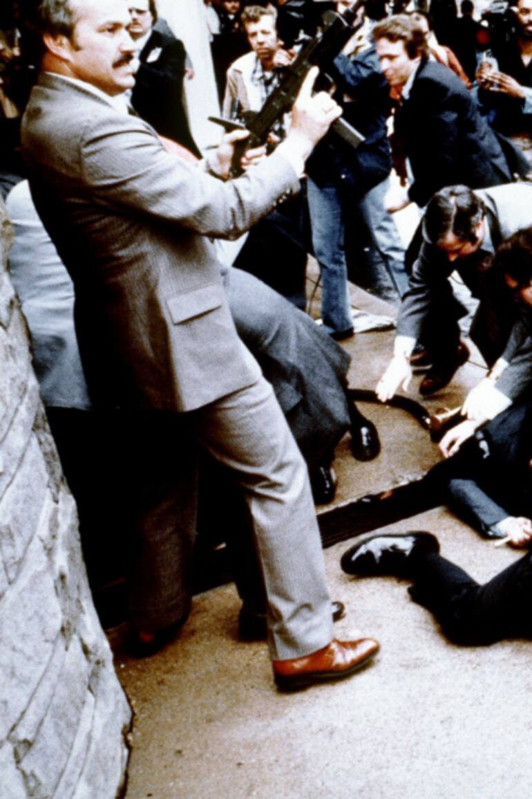 Esta fotografía, tomada por el fotógrafo presidencial Mike Evans el 30 de marzo de 1981, captura la reacción de la policía y los agentes del Servicio Secreto durante el intento de asesinato contra el entonces presidente de EE.UU., Ronald Reagan, tras una conferencia frente al Hotel Hilton en Washington, D.C..