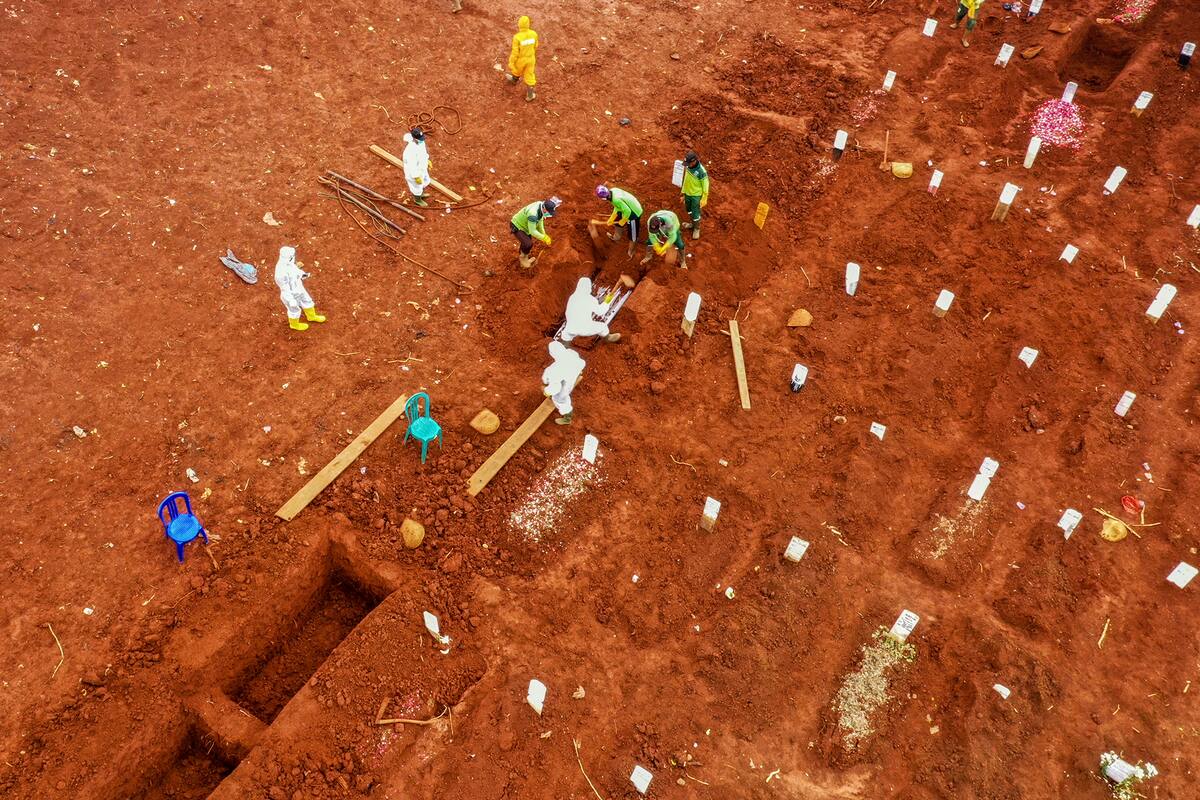 Esta imagen aérea muestra a los trabajadores colocando un ataúd de una víctima del coronavirus en un cementerio en Yakarta, Indonesia, el 15 de abril de 2020