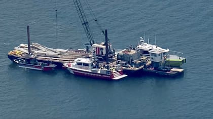Esta imagen muestra al Cuerpo de Bomberos de Miami-Dade, al Cuerpo de Bomberos de la Ciudad de Miami y a otros en botes alrededor de la barcaza