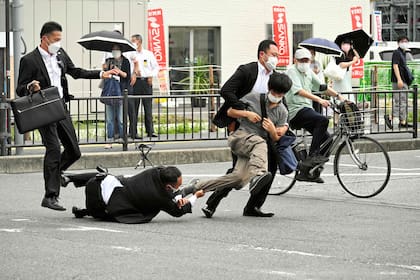 Esta imagen recibida del periódico Asahi Shimbun muestra a un hombre (centro D) sospechoso de dispararle al ex primer ministro japonés Shinzo Abe siendo derribado por la policía en la estación Yamato Saidaiji en la ciudad de Nara el 8 de julio de 2022