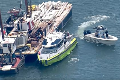 Esta imagen, tomada de un video proporcionado por WSVN-TV, muestra al Cuerpo de Bomberos de Miami-Dade, la Guardia Costera de EE. UU., la policía y otros en botes alrededor de lo que parece ser una barcaza involucrada en un accidente con un grupo de niños y un adulto en un velero durante un campamento de vela, el lunes 28 de julio de 2025 en Miami.