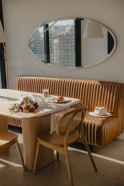 Este departamento en Montevideo proyectado por Consuelo Saravia propone una combinación de madera, esterilla y banco de cuero que llena de carácter un rincón de la cocina.