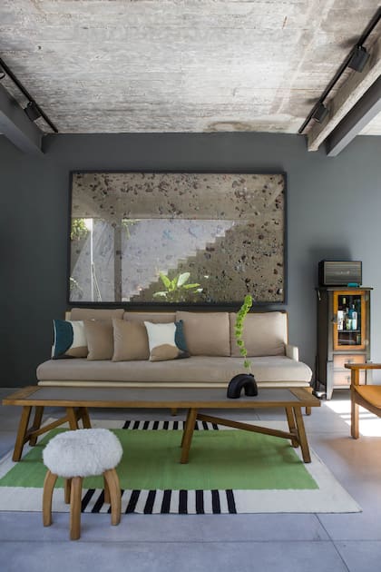 Este fotomontaje de Pablo Tapia que muestra cascotes y piedras de la costa de Vicente López tiene mucho que ver con la casa. También es una obra que rescata la belleza de lo que hay. Sillones y mesa ratona (Eugenio Aguirre). Alfombra (Elementos Argentinos).