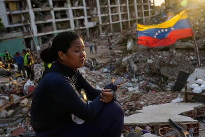 Estefany Landaez permanece sentada entre los escombros de un edificio esperando encontrar a sus dos hijos tras los terremotos en La Guaira