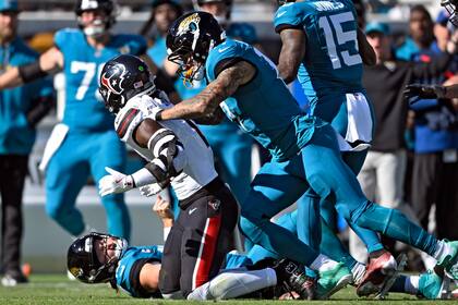 Evan Engram (17), tight end de los Jaguars de Jacksonville, se lanza sobre el linebacker Azeez Al-Shaair (0), de los Texans de Houston, después de que el defensivo golpeara de forma tardía al quarterback Trevor Lawrence (16) durante la primera mitad del juego de la NFL del domingo 1 de diciembre de 2024, en Jacksonville, Florida. (AP Foto/Phelan M. Ebenhack)