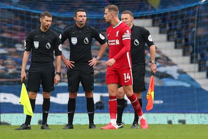 Jordan Henderson de Liverpool habla con el árbitro Michael Oliver y sus asistentes después del partido
