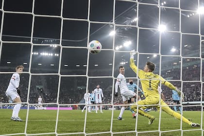 Exequiel Palacios observa expectante cómo la pelota ingresa en el arco de Augsburgo: su gol valió la victoria de Bayer Leverkusen