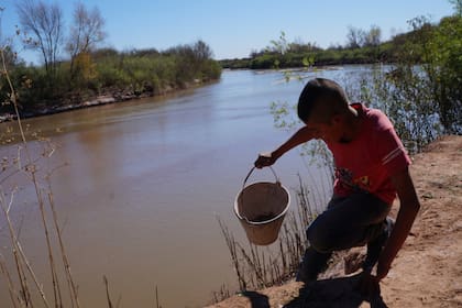 Fabián baja y sube la pendiente del río cargando los baldes