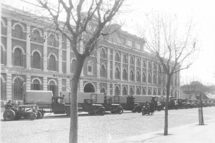 Fachada de la Fabrica Argentina de Alpargatas, la factoría 2, sbre la avenida Patricios, con los camiones de reparto de los productos ostentando las ilustraciones de Florencio Molina Campos