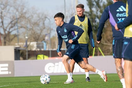 Facundo Buonanotte lleva la pelota, lo mira Alexis Mac Allister. El joven volante de Brighton suma entrenamientos en la selección