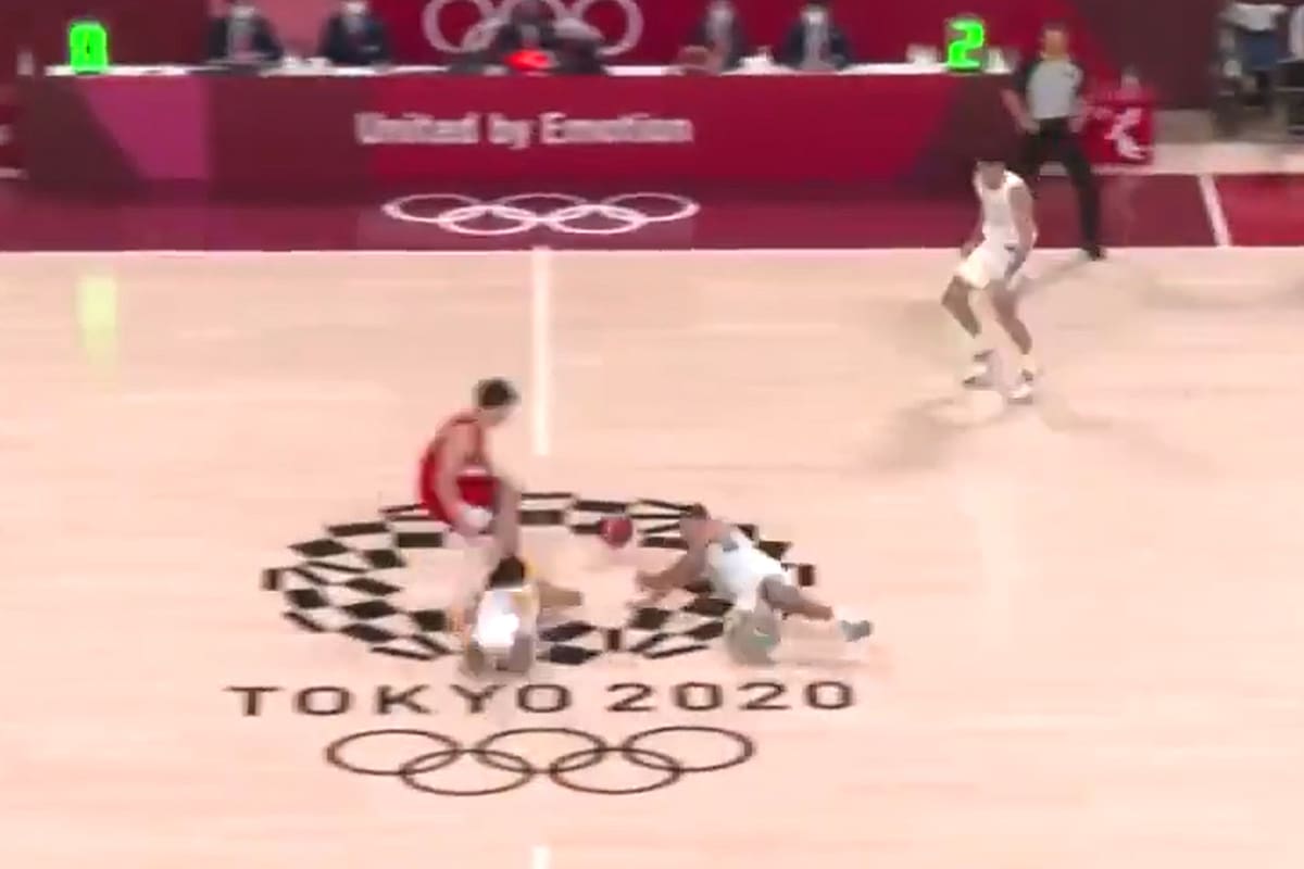 Facundo Campazzo (izquierda) y Luis Scola (derecha) se van al suelo para asegurarse la pelota ante un japonés; la jugada más espectacular del partido terminó con un triple argentino en los Juegos Olímpicos Tokio 2020.