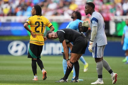 Facundo Tello se toma la pierna lesionada; el árbitro argentino fue reemplazado por su compatriota Darío Herrera, a falta de cinco minutos en RDC vs. Jamaica.