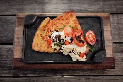 Fainá con queso de cabra, polvo de aceitunas y tomatitos cherry.