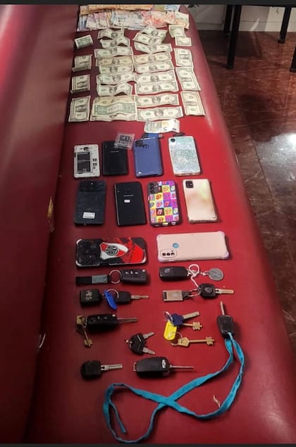 Fajos de billetes en pesos y dólares, junto a celulares y llaves de autos, parte del material incautado en el operativo