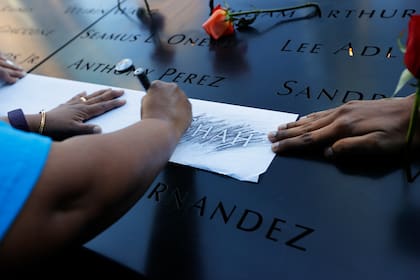 Familiares de Jayesh Shah toman un trozo de papel para calcar su nombre antes de una ceremonia por el vigésimo aniversario de los ataques terroristas del 11 de septiembre de 2001, en el monumento nacional conmemorativo del 11-S en Nueva York, el sábado 11 de septiembre de 2021. (Mike Segar/Pool vía AP)