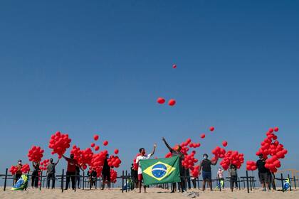 Familiares de un fallecido por COVID-19, junto a una ONG, sueltan globos rojos en homenaje a las víctimas del virus. Copacabana, Río de Janeiro, el 8 de agosto de 2020.