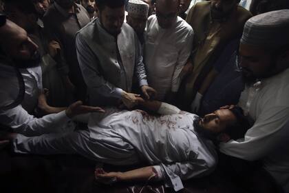 Familiares de una víctima herida por una potente bomba rodean su cama en un hospital de Peshawar, Pakistán, domingo 30 de julio de 2023. (AP Photo/Muhammad Sajjad).