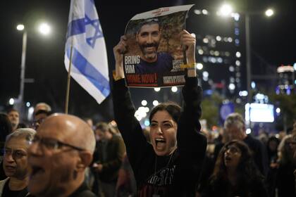 Familiares y partidarios de rehenes israelíes retenidos por Hamas en Gaza sostienen sus fotografías y gritan consignas en una manifestación pidiendo su regreso, en Tel Aviv, Israel