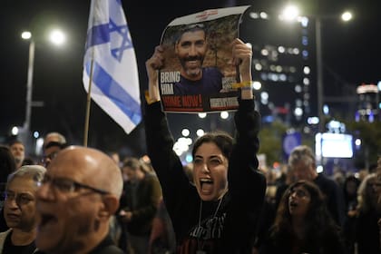 Familiares y partidarios de rehenes israelíes retenidos por Hamas en Gaza sostienen sus fotografías y gritan consignas en una manifestación pidiendo su regreso, en Tel Aviv, Israel