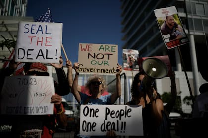 Familiares y partidarios de rehenes israelíes retenidos por Hamas en Gaza sostienen carteles y banderas durante una protesta que pide el regreso de los cautivos, ante el lugar donde celebraba reuniones el secretario de Estado de Estados Unidos, Antony Blinken, en Tel Aviv.