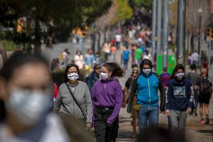 Familias caminan por un bulevar en Barcelona, España, el domingo 26 de abril de 2020, mientras continúa el bloqueo para combatir la propagación del coronavirus. El domingo, a los niños menores de 14 años se les permitirá caminar con sus padres hasta por una hora y dentro de un kilómetro de casa, ter
