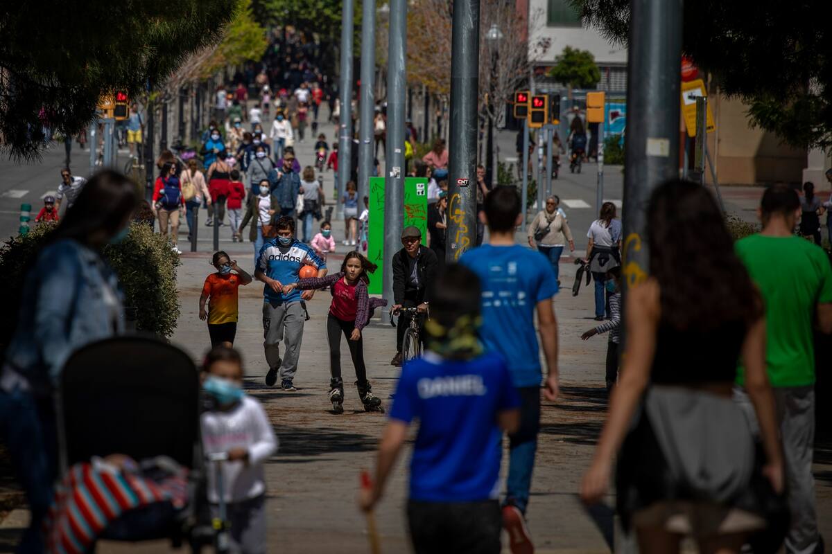 Familias caminan por un bulevar en Barcelona, España, el domingo 26 de abril de 2020, mientras continúa el bloqueo para combatir la propagación del coronavirus. El domingo, a los niños menores de 14 años se les permitirá caminar con sus padres hasta por una hora y dentro de un kilómetro de casa, ter