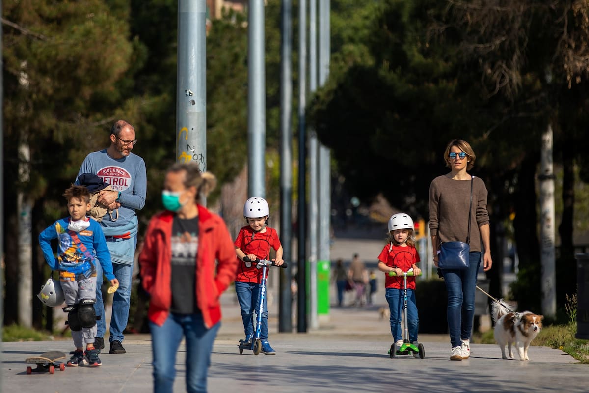 Familias caminan por un bulevar en Barcelona, España, el domingo 26 de abril de 2020, mientras continúa el bloqueo para combatir la propagación del coronavirus. El domingo, a los niños menores de 14 años se les permitirá caminar con sus padres hasta por una hora y dentro de un kilómetro de casa, ter